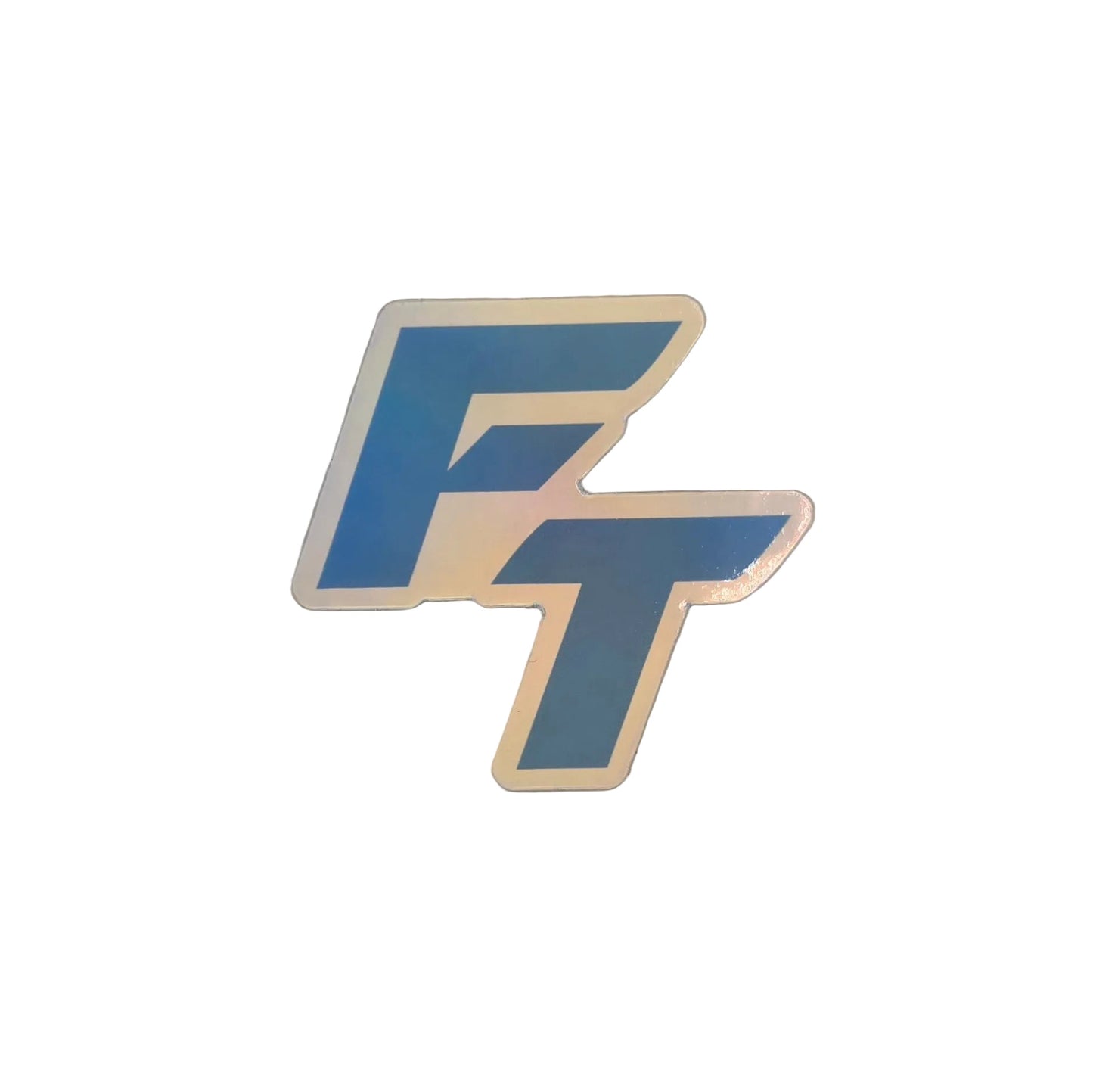 A die-cut sticker featuring the stylized letters 'FT' in blue with a holographic iridescent border, placed on a light gray textured surface.